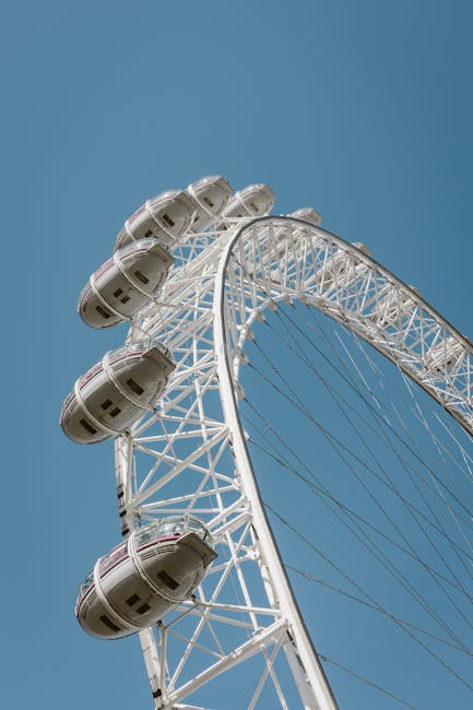 A close-up view of the London Eye Ferris wheel against a clear blue sky, showcasing its white structural framework and multiple glass capsules. The capsules are evenly spaced along the circular rim, reflecting sunlight and appearing clean and well-maintained. The wheel's supports and spokes are visible, emphasizing its large scale. This image highlights the structural design and cleanliness of the Ferris wheel, which is situated outdoors in an urban setting. The focus is on the wheel's surface and overall condition, illustrating a pristine state suitable for industries emphasizing hygiene and maintenance such as professional cleaning or surface care services. Carpet Cleaners Lambeth may utilize similar attention to surface cleanliness and detail in their deep cleaning and sanitisation offerings, emphasizing how well-maintained equipment and surfaces contribute to overall hygiene.